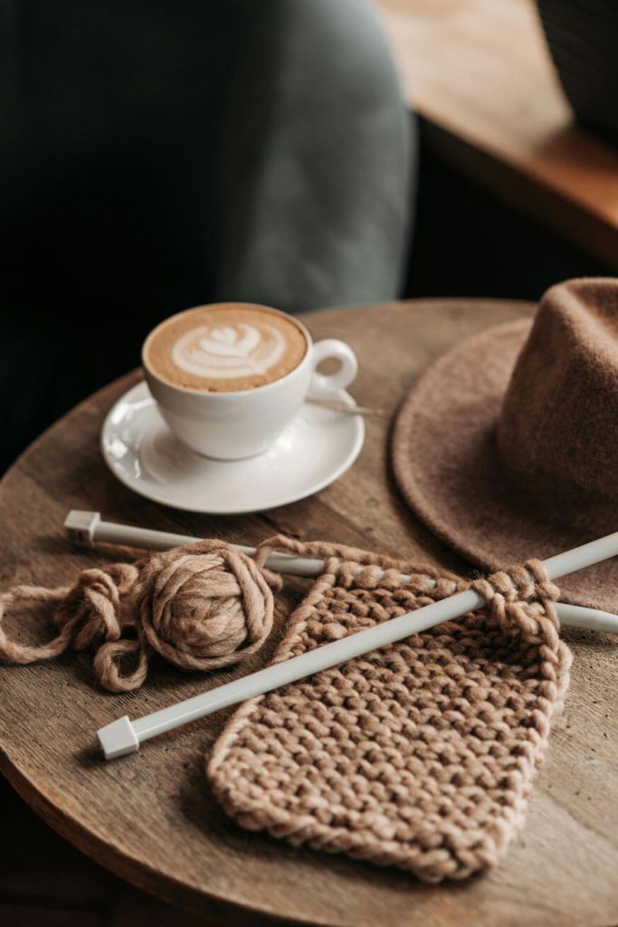 coffee-drink-beside-a-knitted-material-on-wooden-table